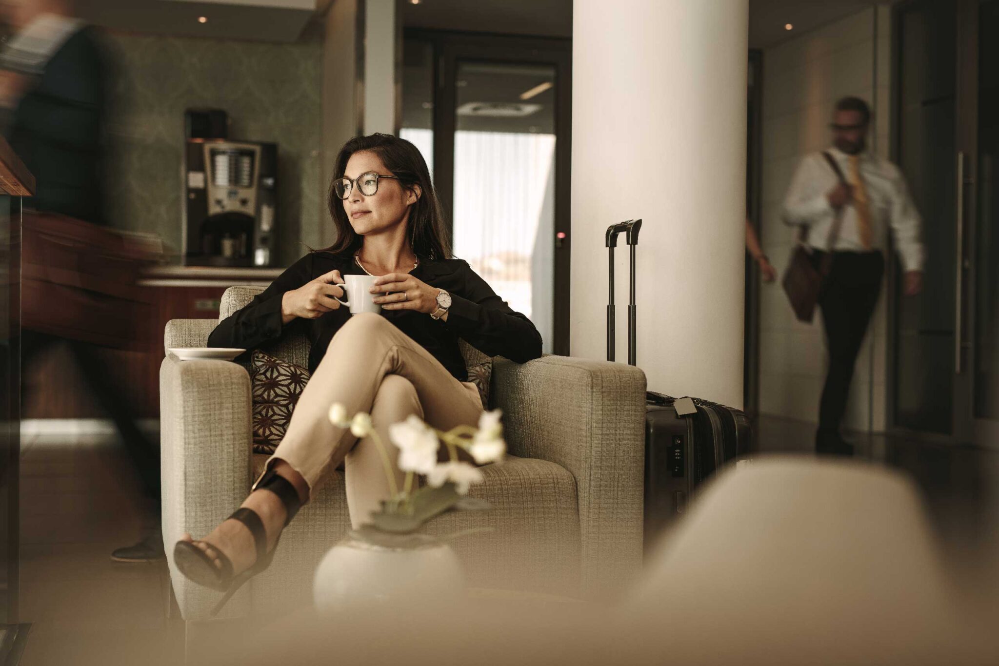 a woman sitting in a lobby, drinking coffee