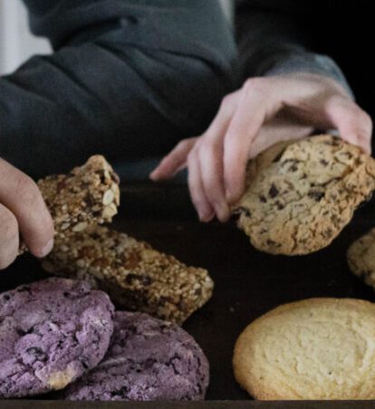 people helping themselves to a box of cookies