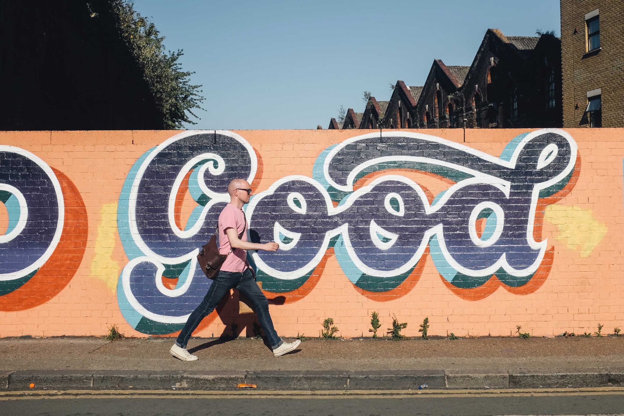 a man walking next to a colorfully painted wall