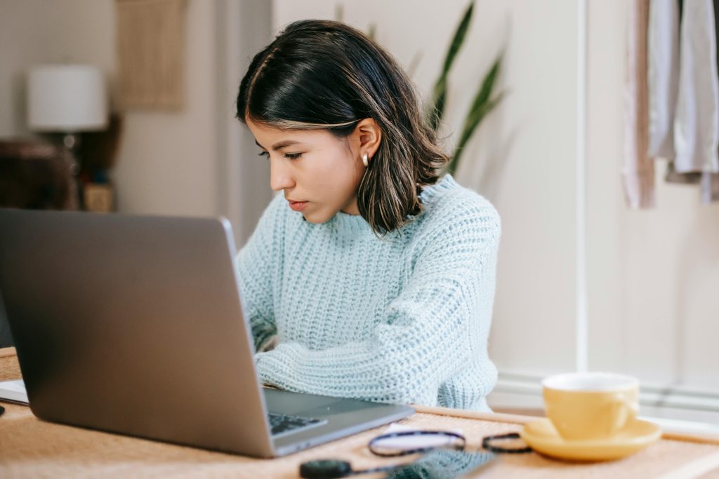 female student using laptop in apartment