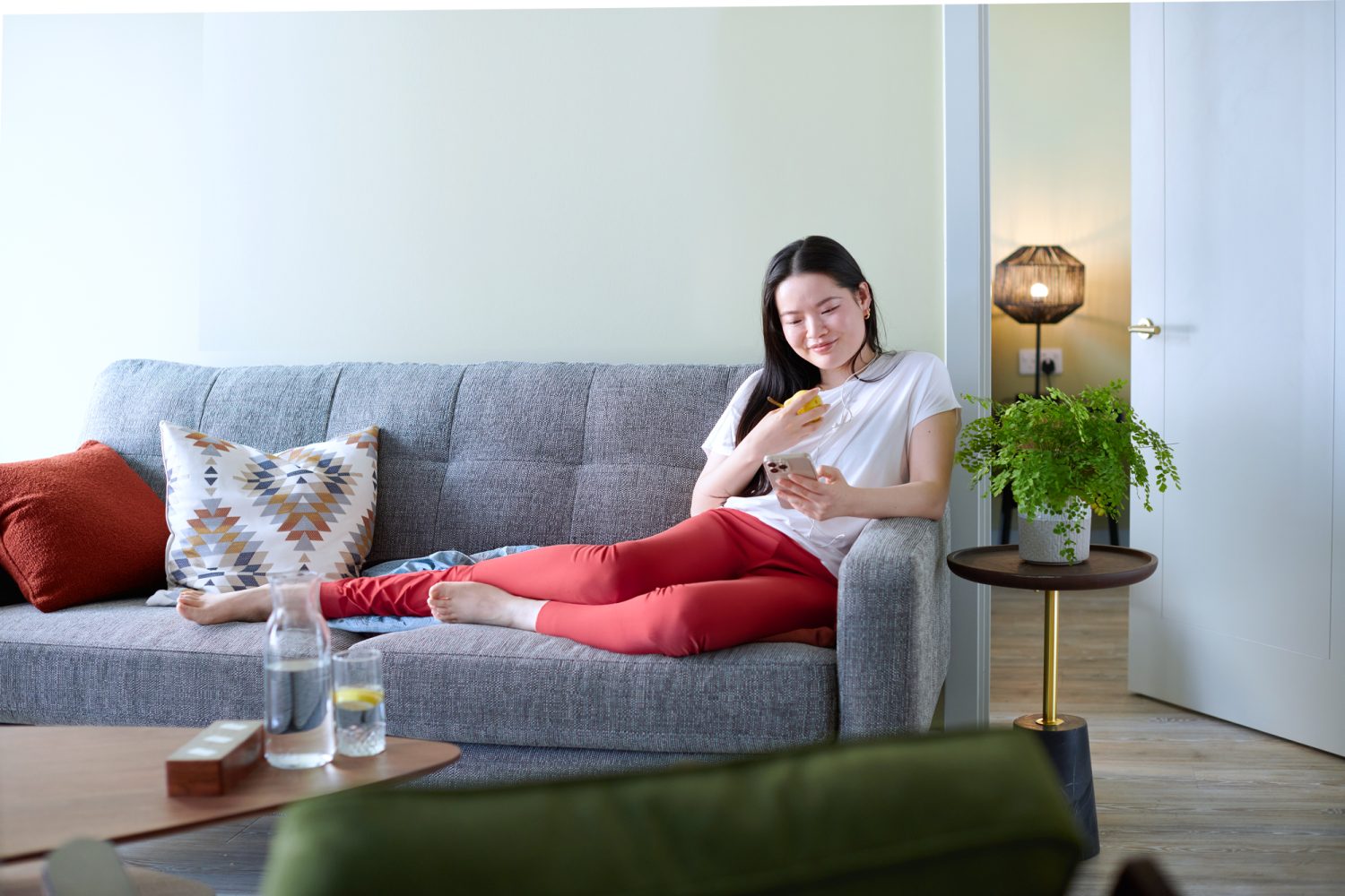 Woman laying on her couch on her phone.