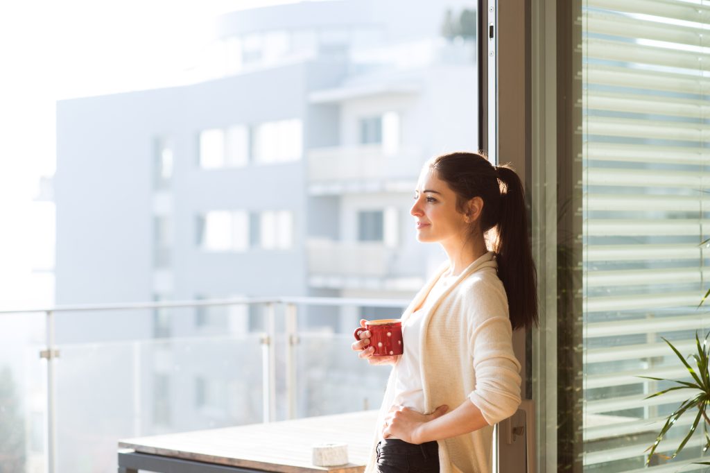 Woman relaxing on balcony holding cup of coffee or tea
