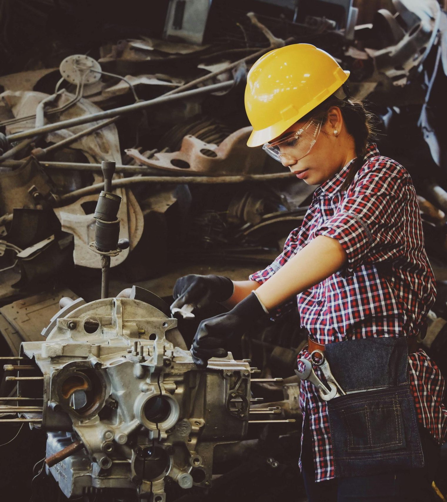 Woman Wears Yellow Hard Hat Holding Vehicle Part